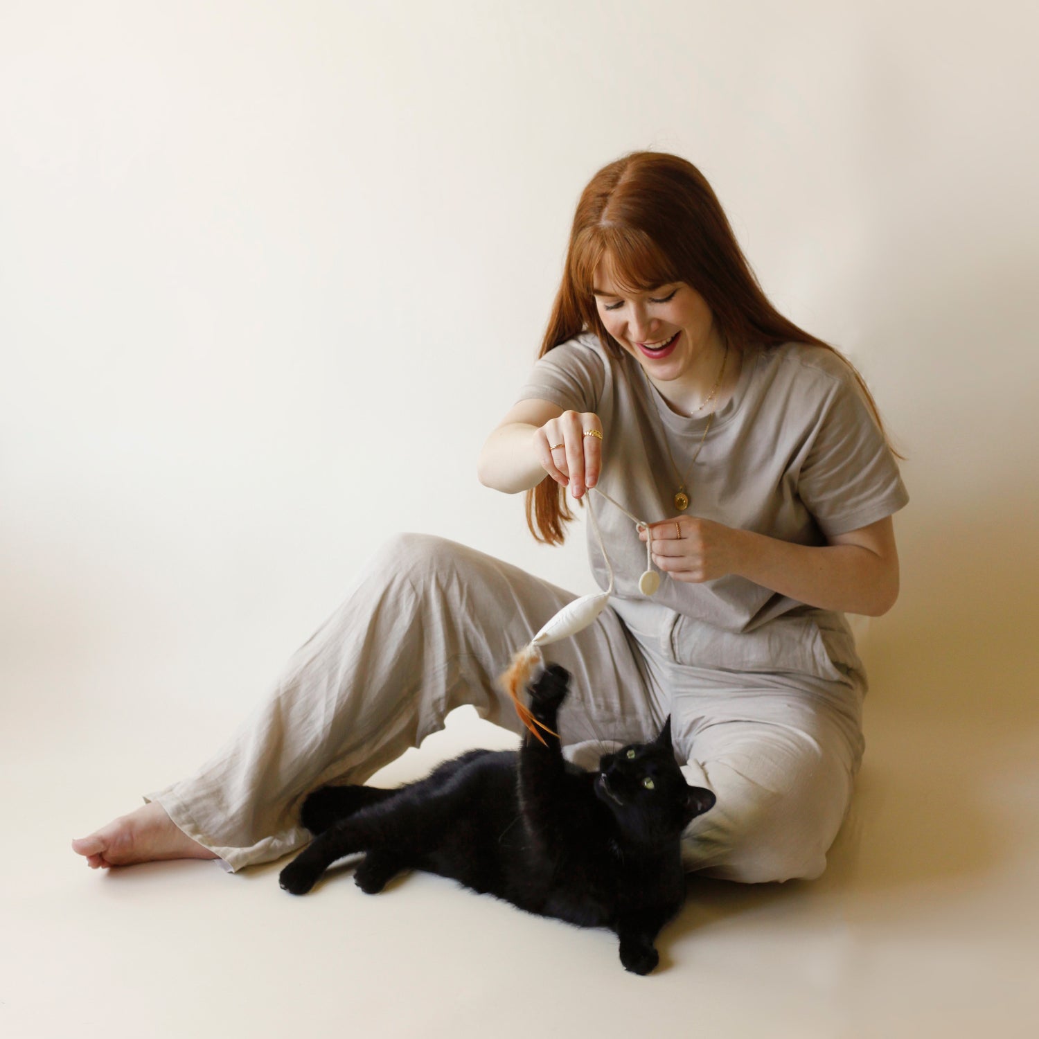 Woman plating with cute cat and cute fish toy in linen